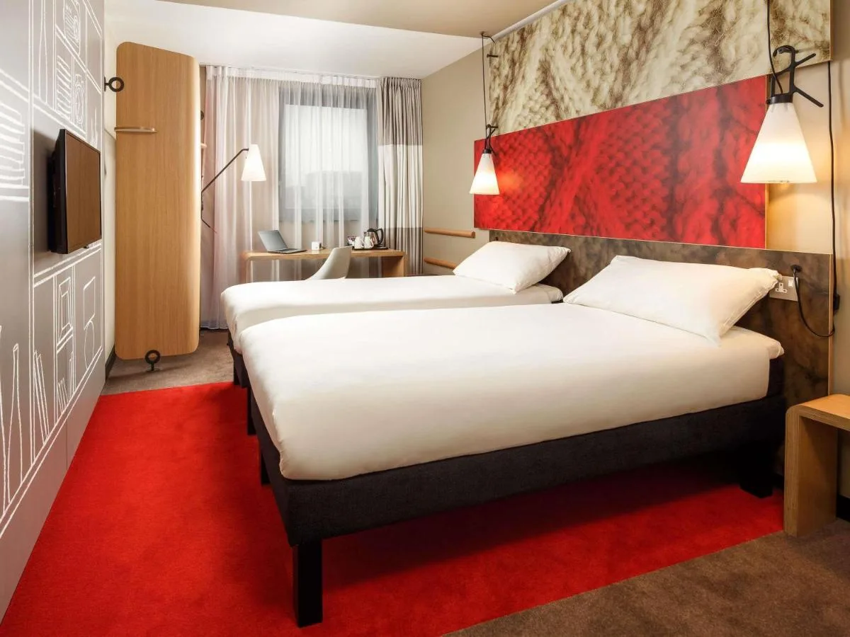 a hotel room with two beds and a red carpet at ibis Cambridge Central Station in Cambridge