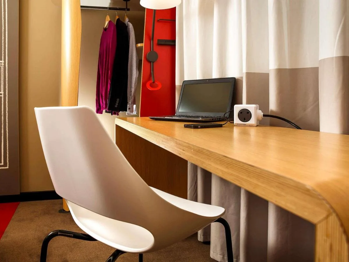 a desk with a laptop and a white chair at ibis Cambridge Central Station in Cambridge
