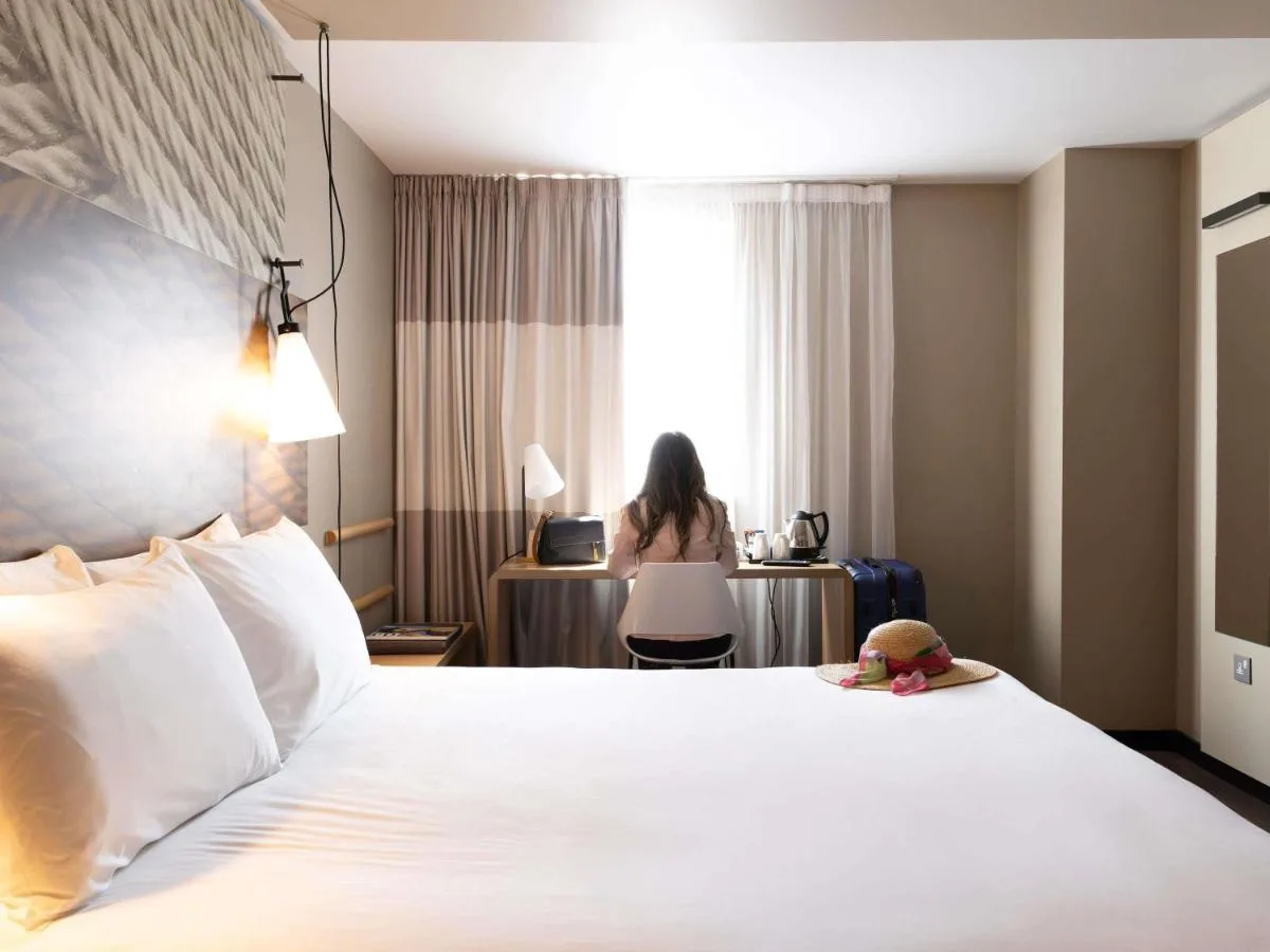 a woman sitting at a desk in a hotel room at ibis Cambridge Central Station in Cambridge
